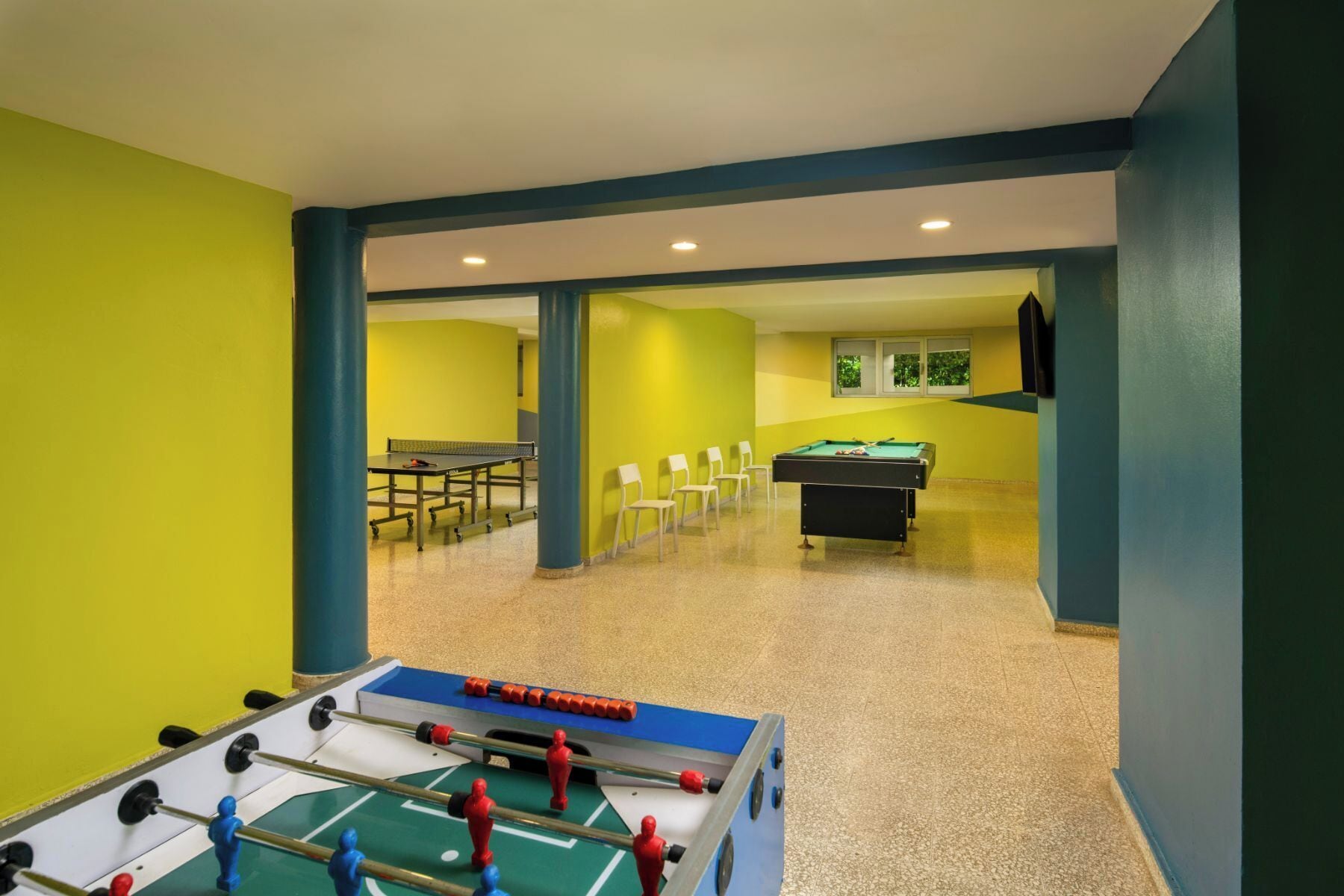 A recreational area with a foosball table, pool table, and seating area.