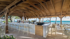 Eine Strandbar mit Holzbalken, einer Theke und Sitzbereichen.