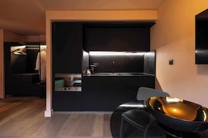 A modern kitchen with a black countertop, a sink, and a stainless steel bowl on a chair. - Whitworth Locke (Manchester)