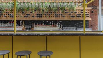 A bar area with a wine rack, stools, and a yellow wall.