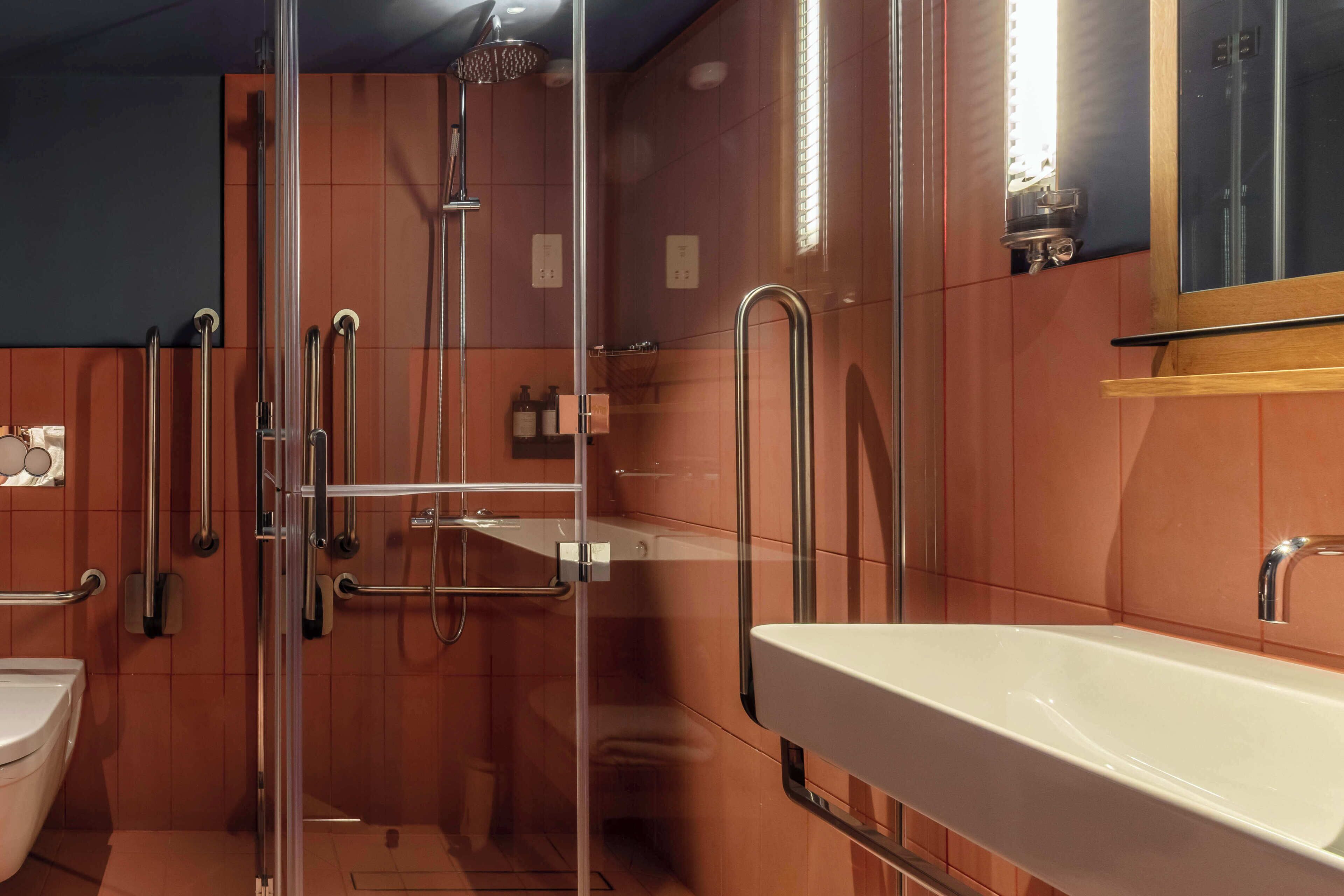 A modern bathroom with a glass-enclosed shower, a white sink, and a mirror.