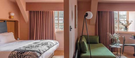 Ein Hotelzimmer mit einem Bett, einem grünen Sofa, einem kleinen Tisch mit einer Vase und einem Fenster mit Vorhängen.
