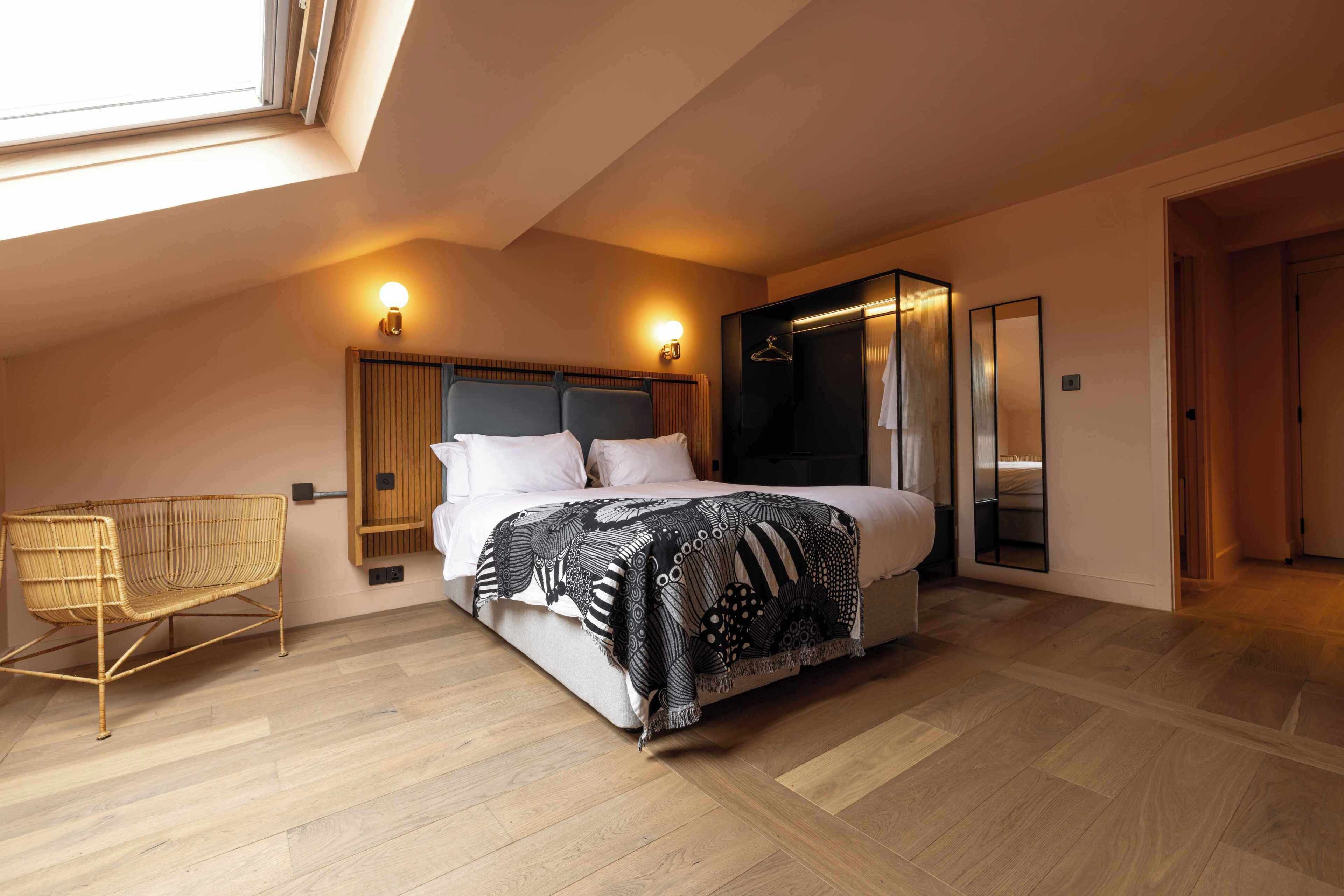 A bedroom with a bed, a chair, a wardrobe, and a mirror.