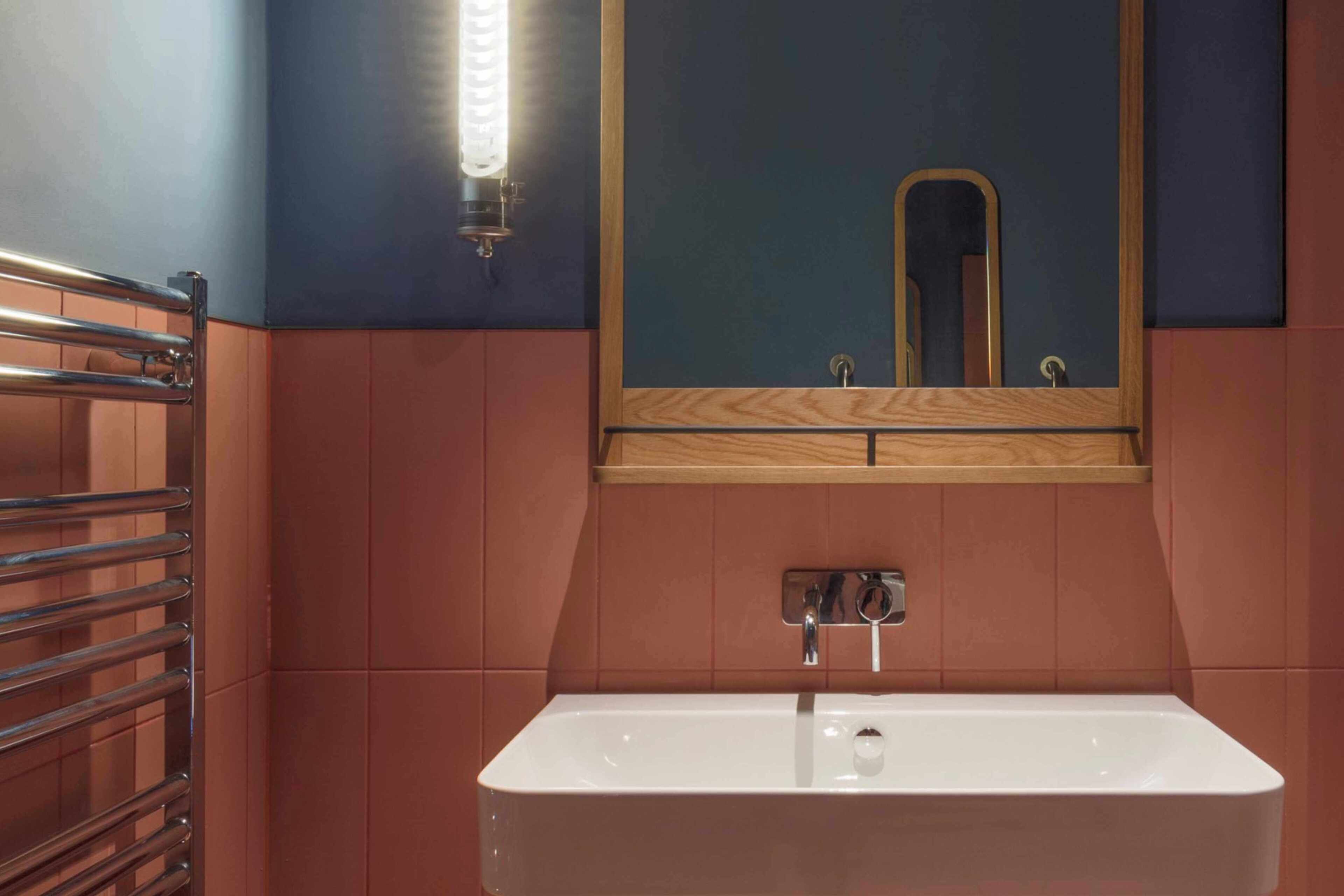 A bathroom with a white sink, a mirror, and a towel rack.