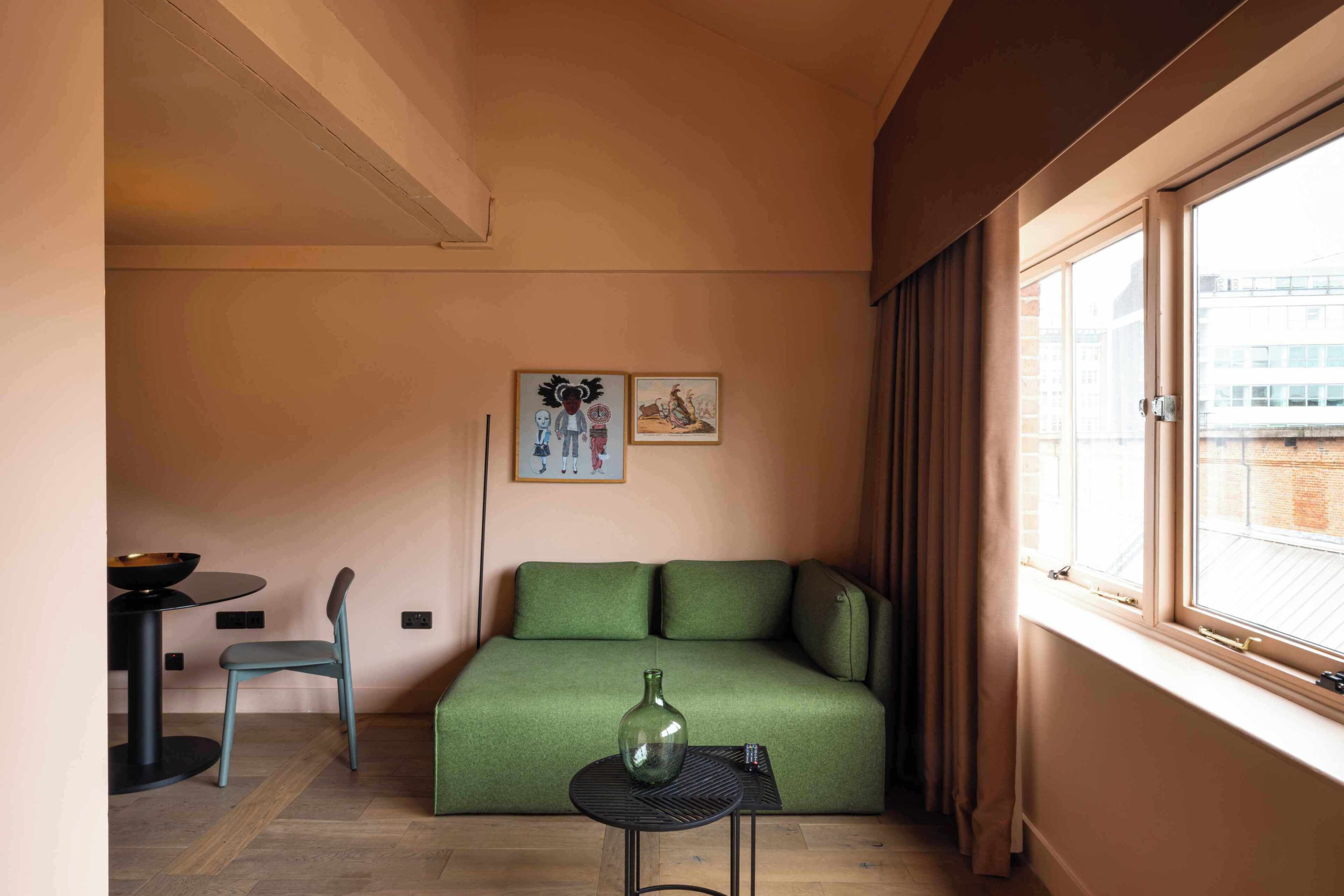 A compact living space with a sofa, a small table, a chair, and a window with curtains.