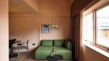 A compact living space with a sofa, a small table, a chair, and a window with curtains.