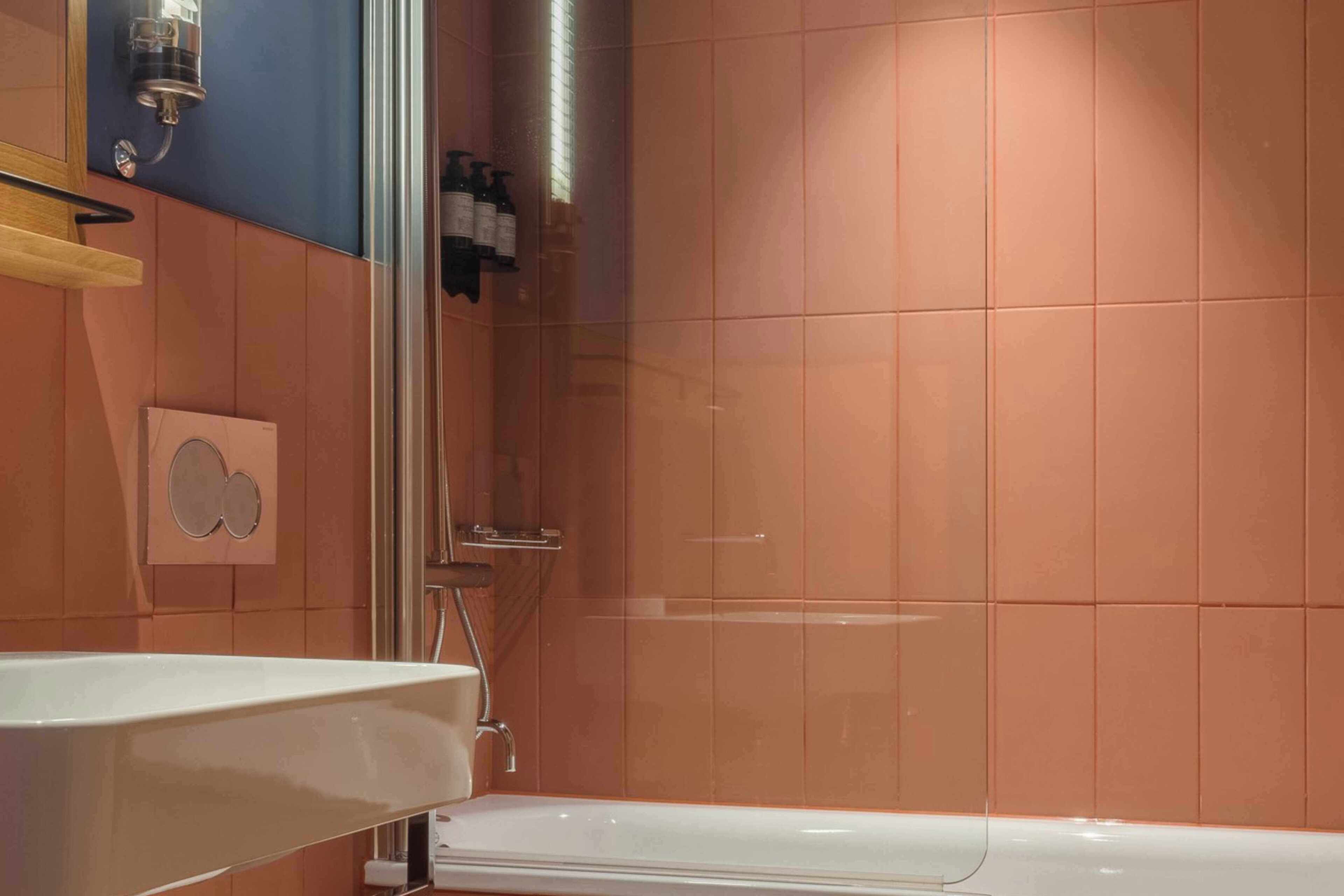 Une salle de bain avec une baignoire blanche, un espace douche et une étagère murale contenant des articles de toilette.