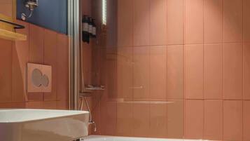 Une salle de bain avec une baignoire blanche, un espace douche et une étagère murale contenant des articles de toilette.