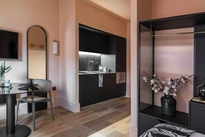 Une cuisine moderne avec un plan de travail noir, un évier et un meuble noir. On y trouve une table à manger avec une chaise, un miroir et un vase avec des fleurs.
