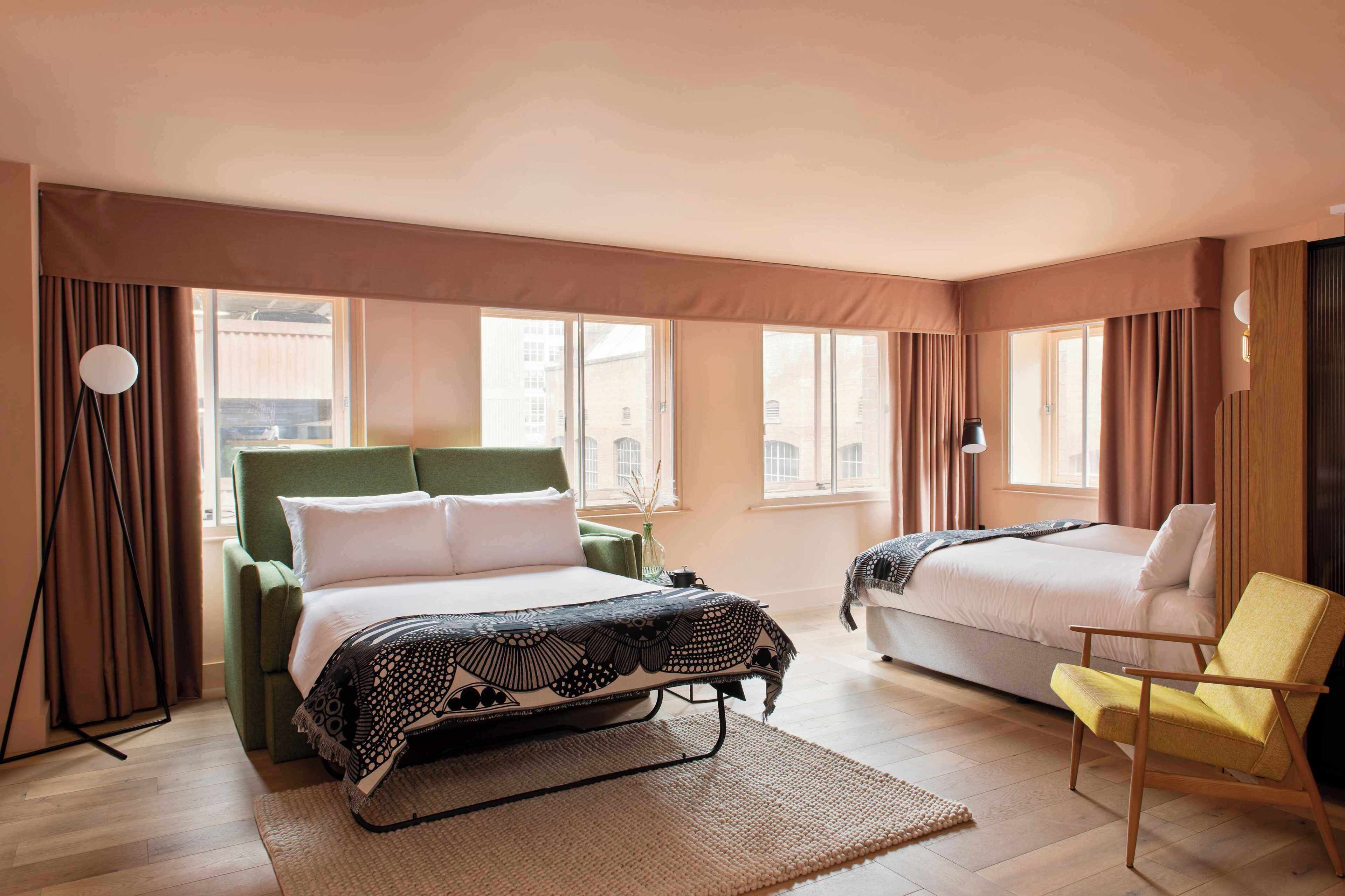 A hotel room with a bed, a chair, and a window.