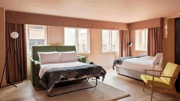 Una habitación de hotel con cama, una silla y una ventana.