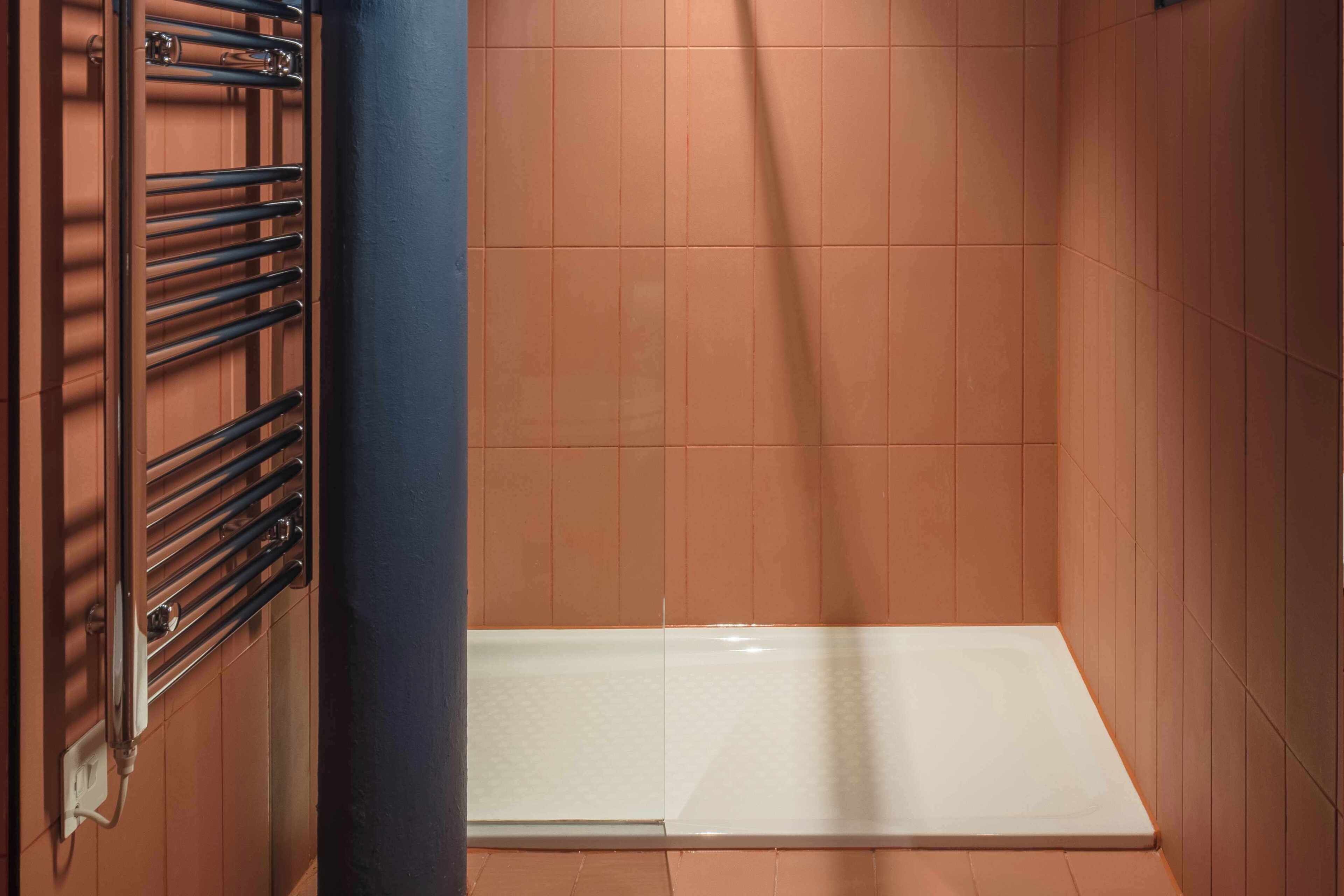 A bathroom with a shower, a towel rack, and a tiled floor.