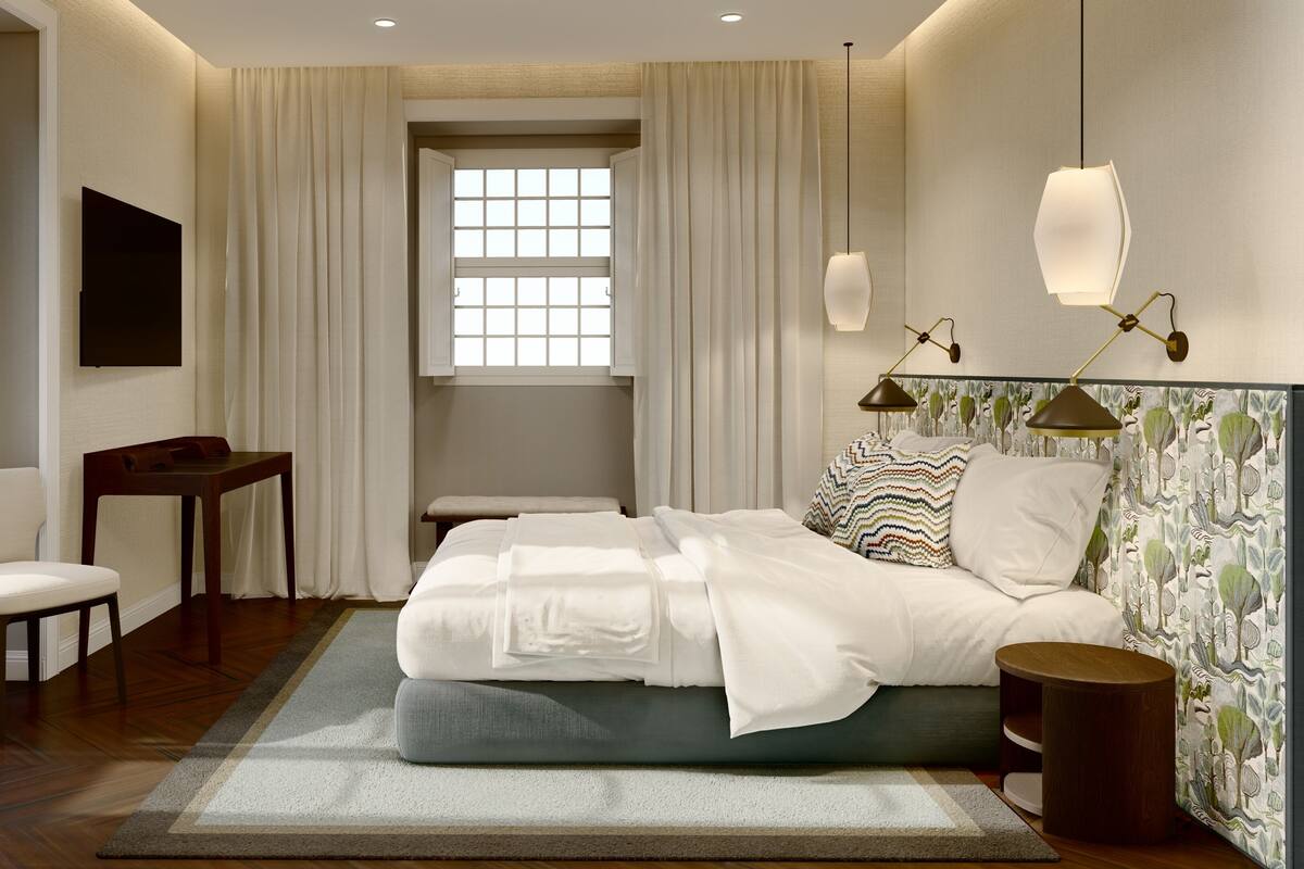 A hotel room with a bed, a desk, a chair, and a window with curtains.