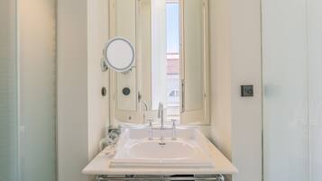 Un baño con lavabo blanco, un espejo y un perchero para toallas.