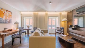 Una sala de estar moderna con sofá, sillones, una mesa de centro, escritorio y televisor.