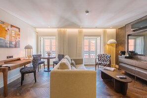 A modern living room with a sofa, chairs, a coffee table, a desk, and a television. - Europe Lisboa Boutique Hotel (Lisbon)