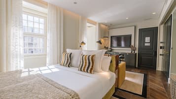 A hotel room with a large bed, a TV, a desk, and a view of the city.