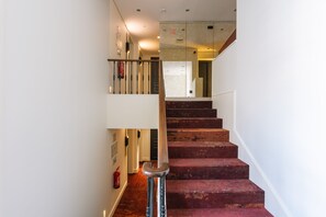 A staircase with red carpeted steps, a metal handrail, and a fire extinguisher on the wall. - Europe Lisboa Boutique Hotel (Lisbon)