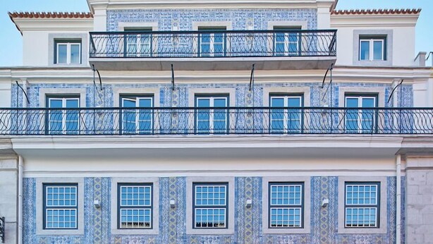 Um edifício com vários andares, fachada em azulejos, varandas e lojas.