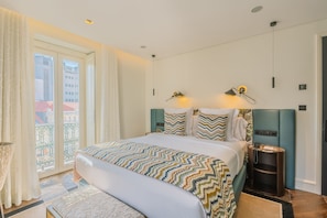 A hotel room with a large bed, a bedside table, a lamp, and a view of the outside. - Europe Lisboa Boutique Hotel (Lisbon)