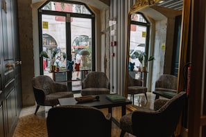 Una habitación con cuatro sillones estampados, una mesita y vistas a la calle.