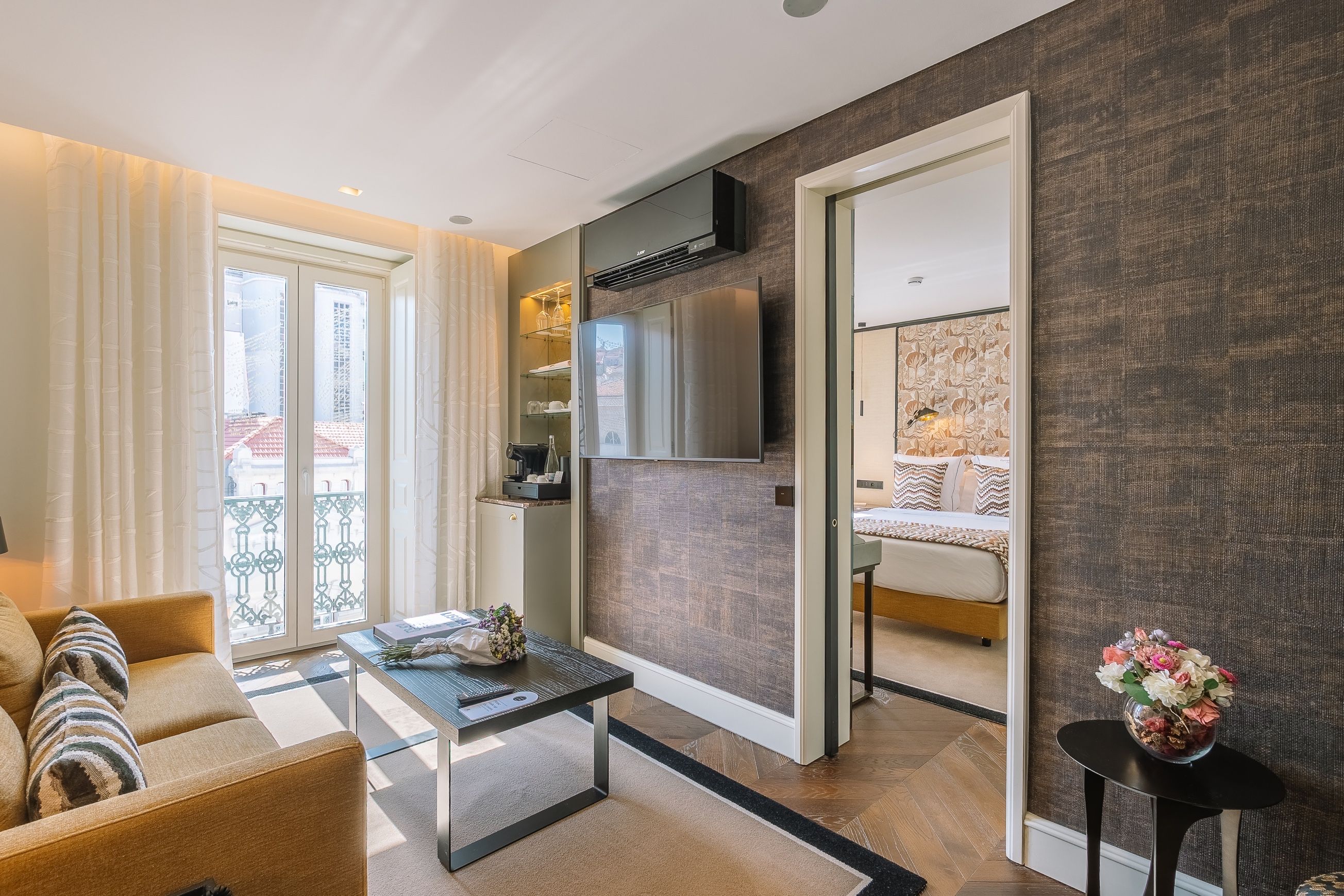A modern living room with a sofa, coffee table, and a view of the city through large windows.