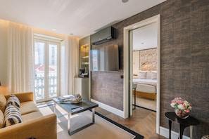 A modern living room with a sofa, coffee table, and a view of the city through large windows. - Europe Lisboa Boutique Hotel (Lisbon)