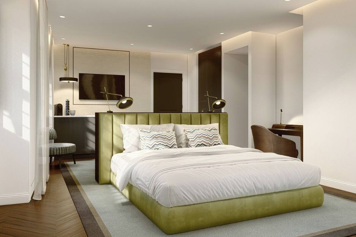 A modern bedroom with a green upholstered bed, a desk, and a chair.
