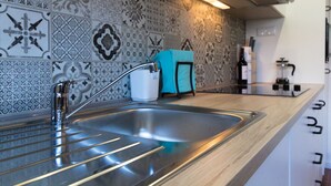 A kitchen with a stainless steel sink, patterned backsplash, and modern appliances.