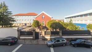 A street view with a red building, a blue building, and a white building. There are cars parked on the street and a pedestrian crossing.