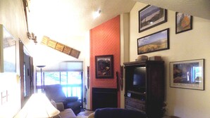 A living room with a fireplace, a television, and a sofa. - Angel Fire Chalet (Angel Fire)