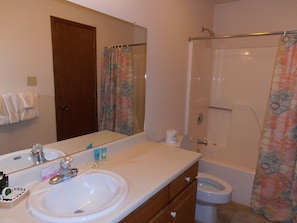 A bathroom with a sink, mirror, toilet, and shower curtain. - Angel Fire Chalet (Angel Fire)