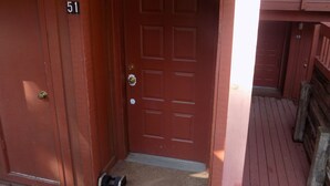 A wooden door with a number plate, a doormat, and a small step leading to a porch. - Angel Fire Chalet (Angel Fire)
