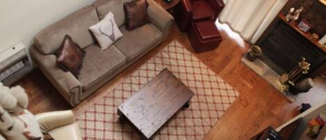 Una sala de estar con sofá, un sillón rojo, una mesa de centro de madera y una chimenea.