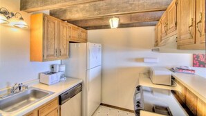 A compact kitchen with wooden cabinets, a white refrigerator, a toaster, and a sink. - Bella Vista (Angel Fire)