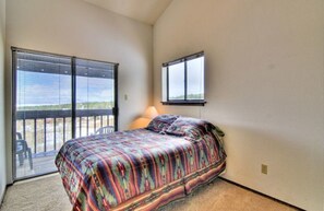 Een slaapkamer met een bed, een raam en een balkon.