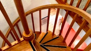 A wooden spiral staircase with a handrail and a wooden floor. - Benchmark (Angel Fire)