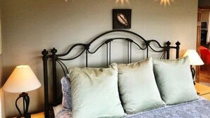 A bedroom with a bed, two wall-mounted lamps, and a framed artwork on the wall. - Benchmark (Angel Fire)