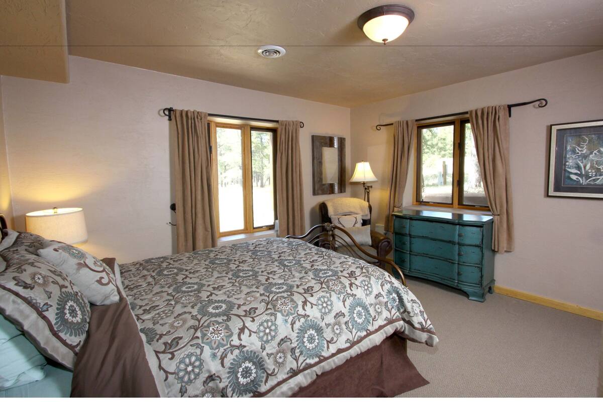 A bedroom with a bed, dresser, lamp, and curtains.