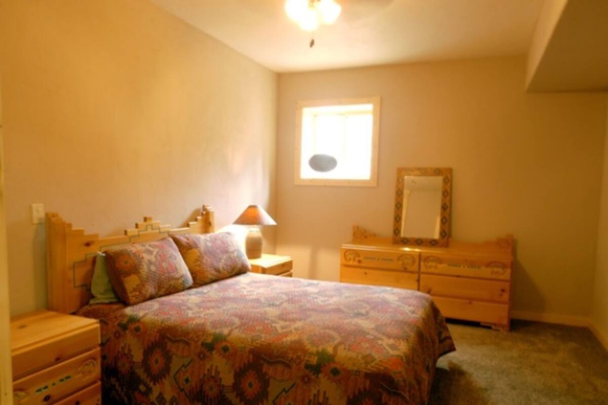A bedroom with a bed, dresser, nightstand, and a window.