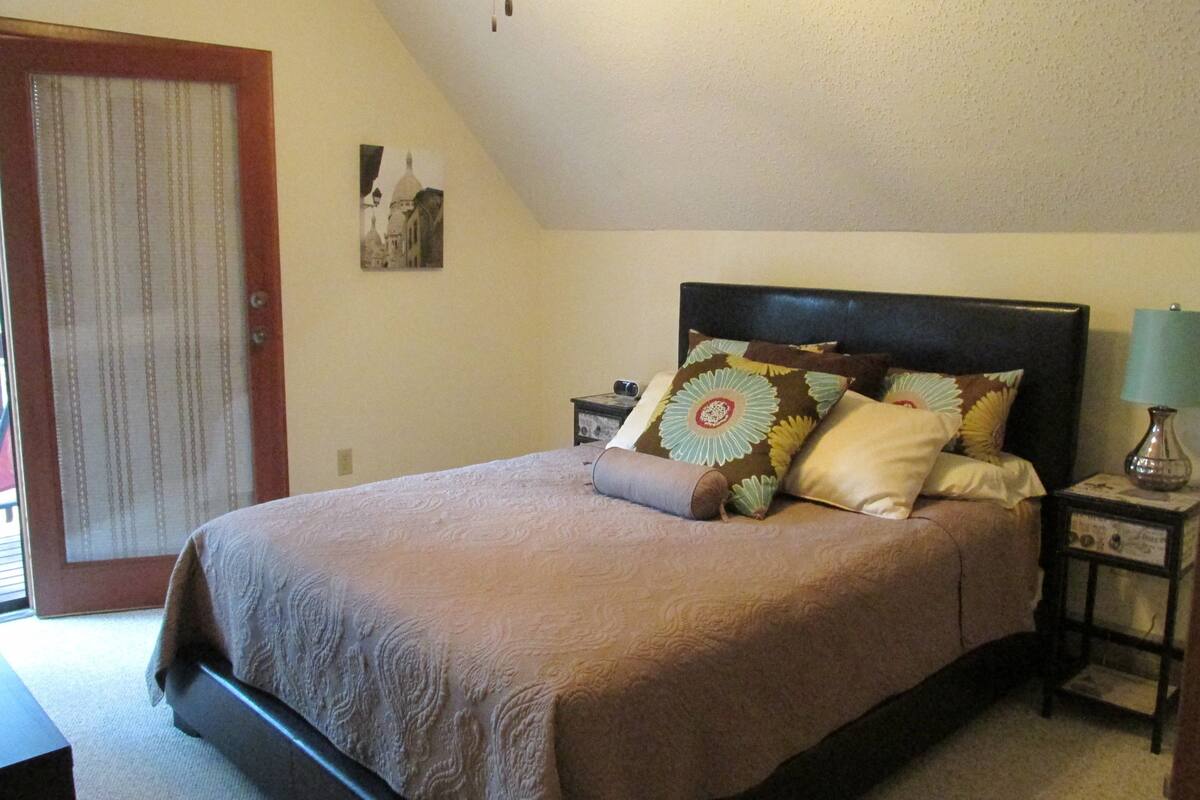 A bedroom with a bed, a nightstand, a lamp, and a door.