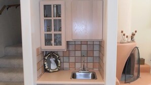 A compact kitchen with a sink, cabinets, and a tiled backsplash. - Mountain Haven (Angel Fire)