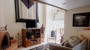 A living room with a sofa, a TV, a wooden cabinet, and a patterned rug. - Mountain Haven (Angel Fire)