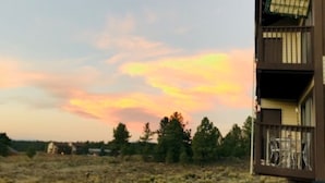 A building with a balcony and a view of a sunset over a field. - Mountain Meadows (Angel Fire)