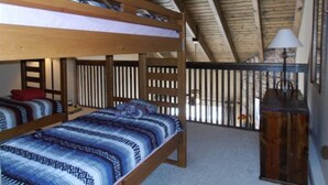 A bunk bed room with a wooden ceiling and a view of the outside. - Mountain Meadows (Angel Fire)