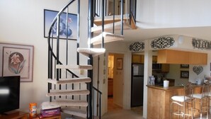 En moderne opholdsstue med en spiraltrappe, et lille siddeområde, et køkken og en bar.