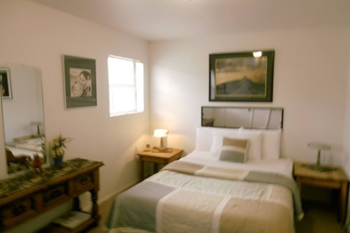 A bedroom with a bed, a nightstand, a dresser, and a window.