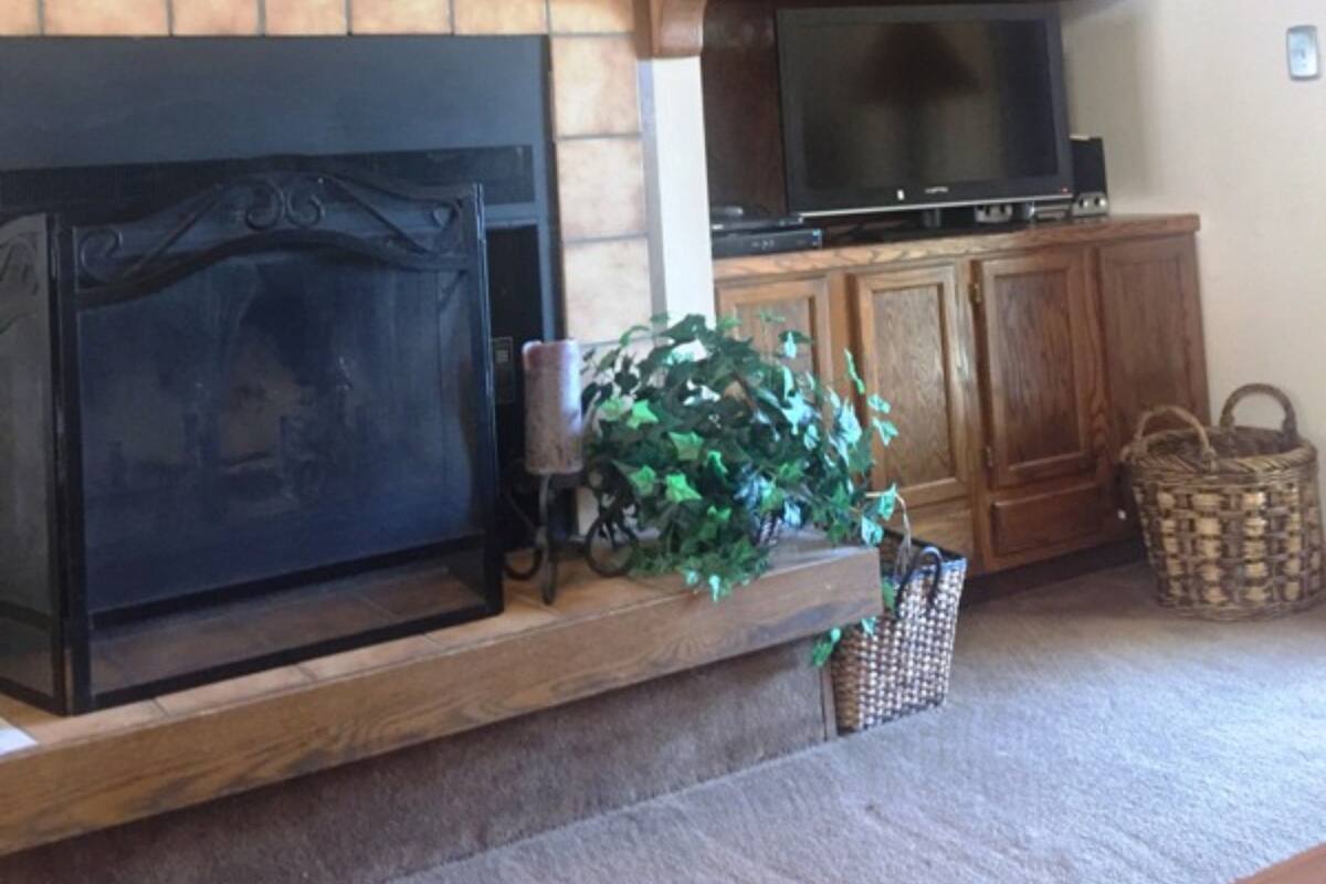 A living room with a fireplace, TV, wooden shelves, and decorative items.