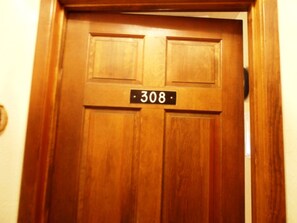 A wooden door with a black number plate displaying '308'. - The Wren (Angel Fire)