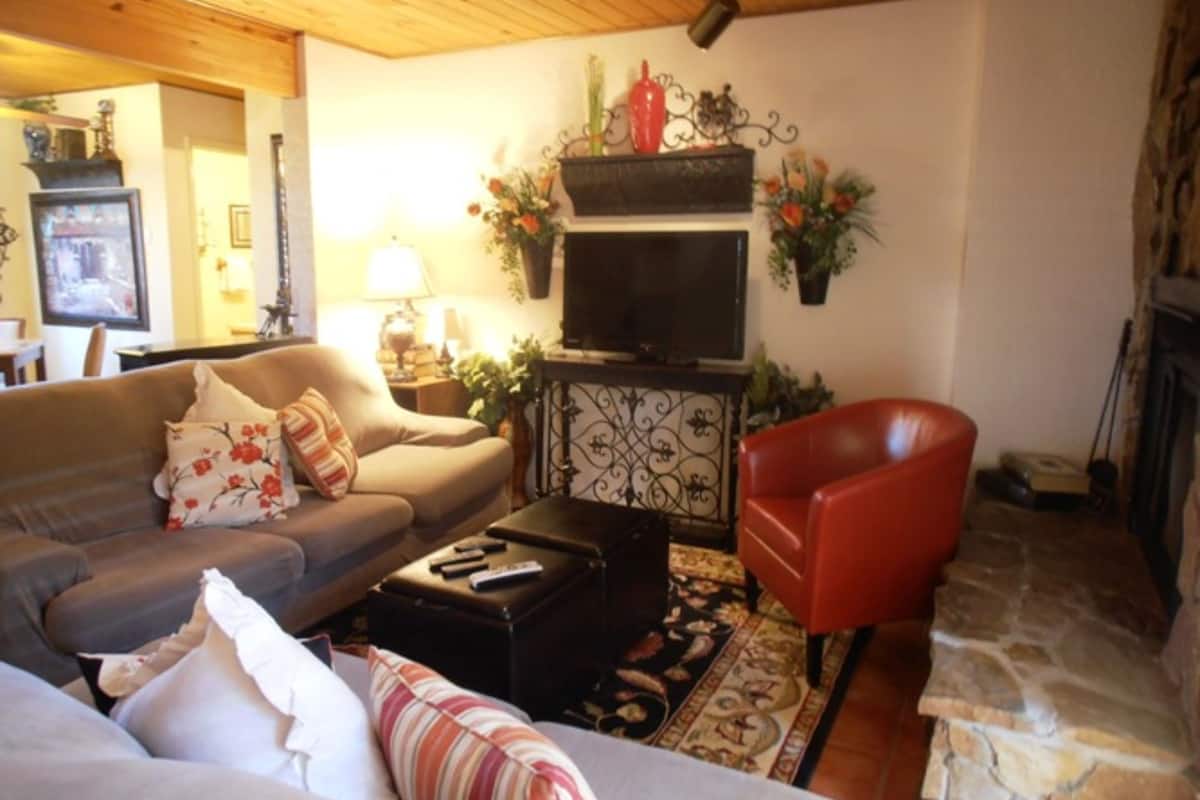 A cozy living room with a sofa, armchair, and a fireplace.
